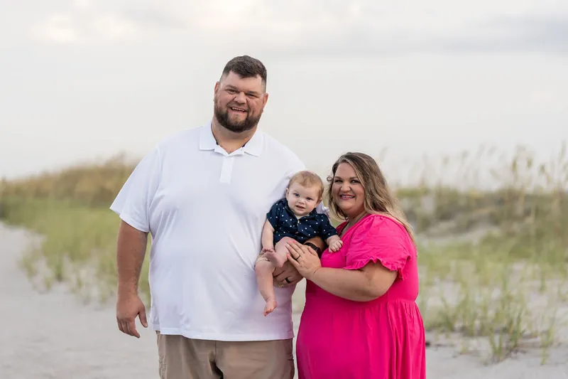 Brook and Josh pose with their laughing son between the dunes at Vilano Beach.