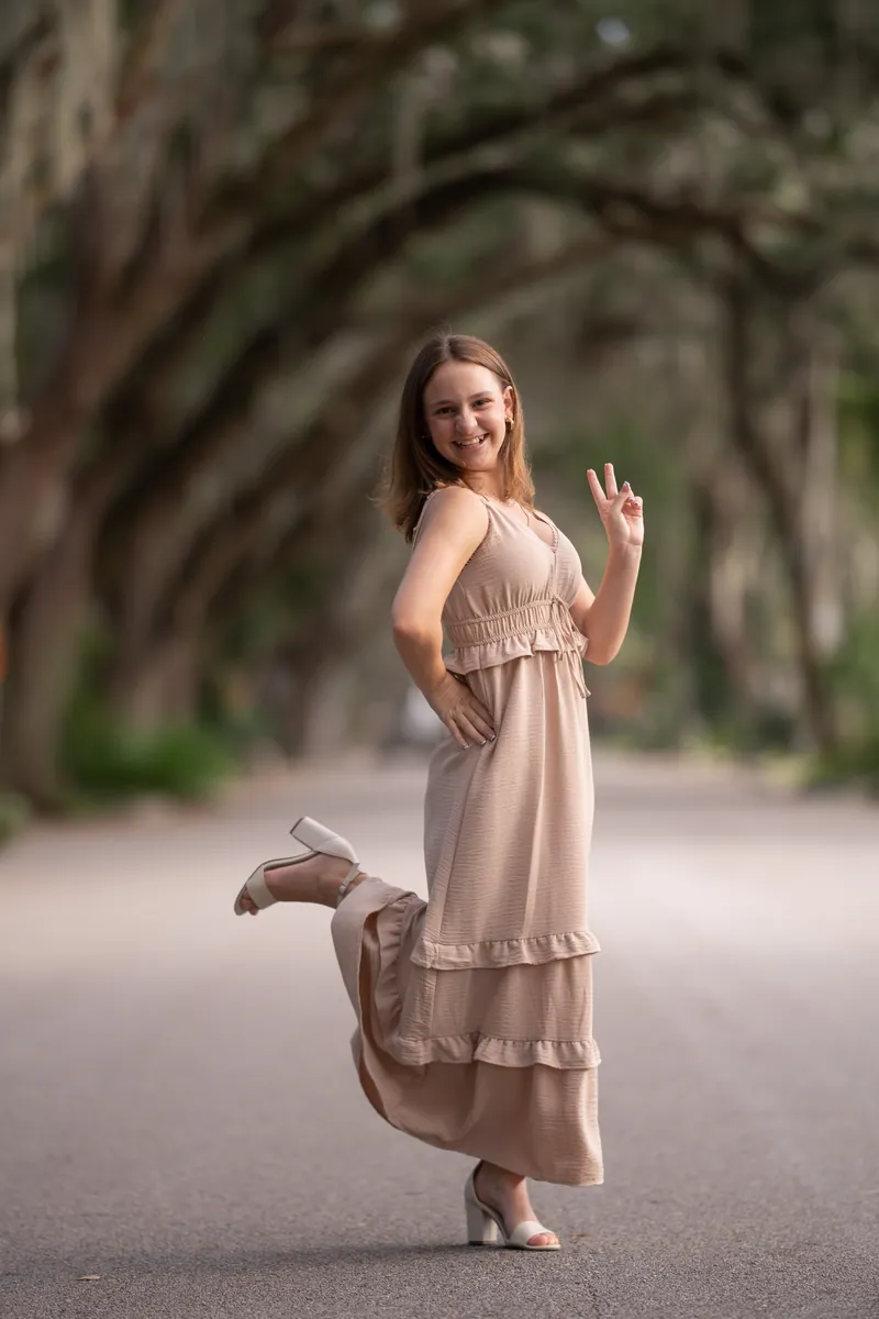 Older sister in playful pose kicking leg back with peace sign