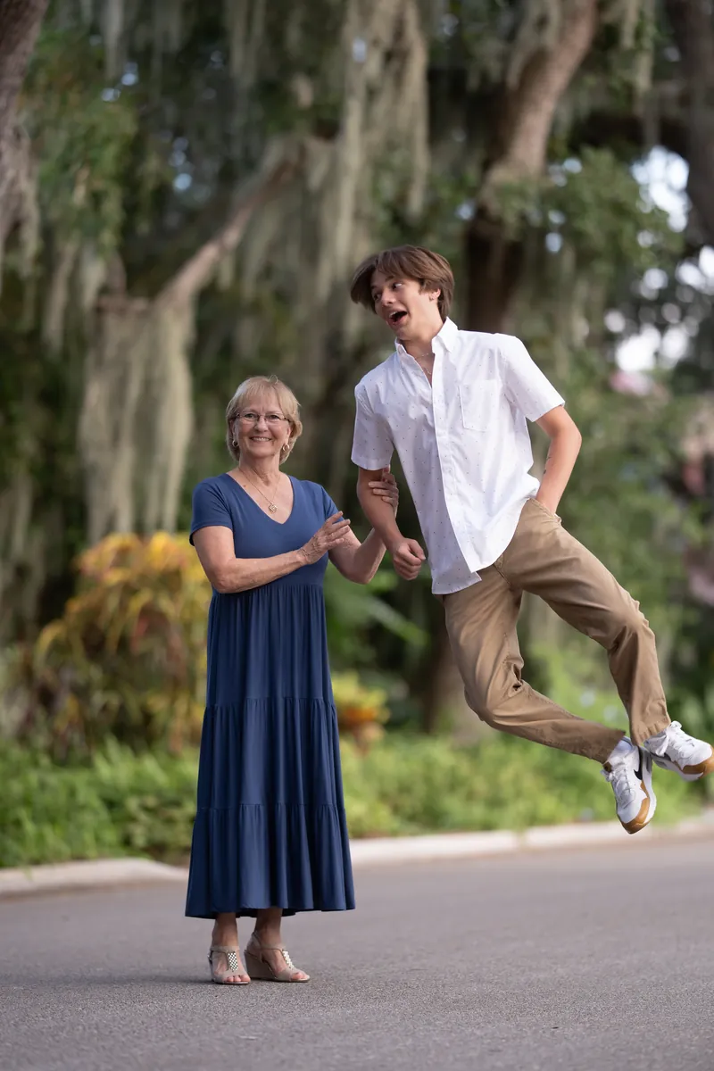 Grandson jumping mid-air while grandmother laughs