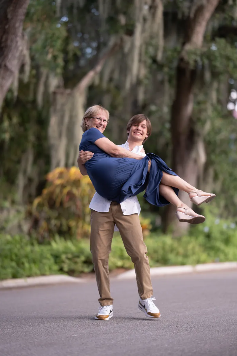 Grandson lifting grandmother in his arms, both laughing