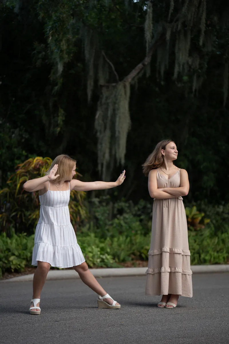 Sisters in playful karate-style pose, one pushing air toward the other