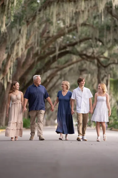St. Augustine family photographer captures multigenerational family walking beneath oak canopy on Magnolia Street