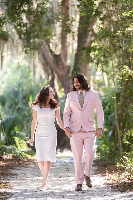 The two walk side-by-side down the boardwalk trail, bathed in filtered green light from overhanging trees.