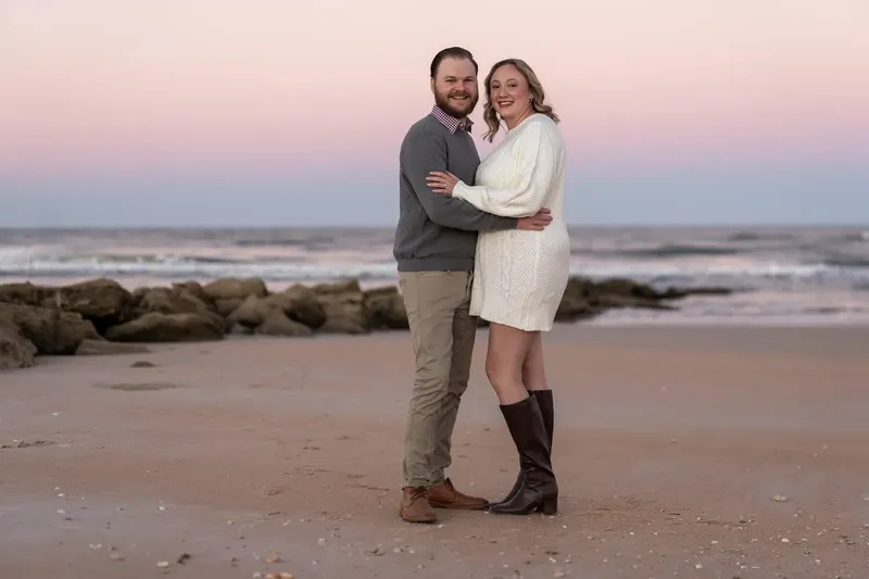 Carli and Jeff beach portrait with pink sunset sky and coquina rocks