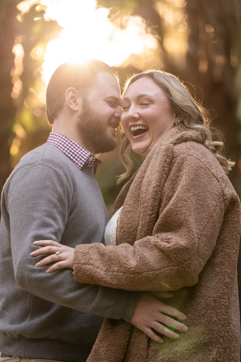 Couple laughing together outdoors at golden hour with warm sunlight