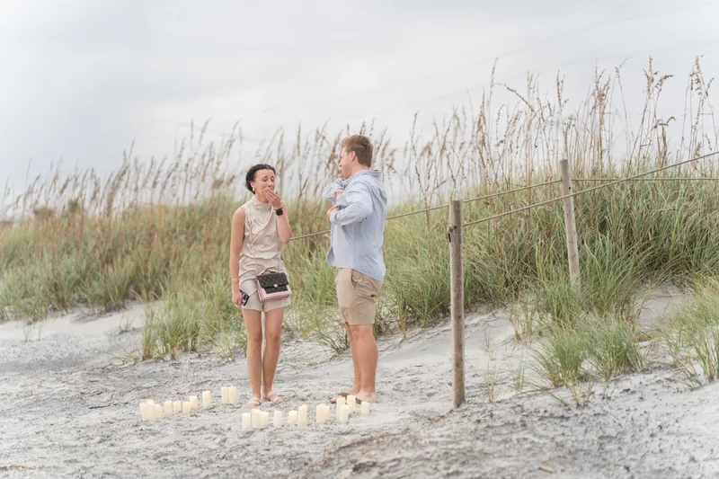 Two people face each other on the sand between beach fence and dune grasses at Mussallem Beachfront Park, St. Augustine.