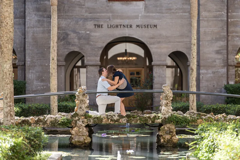 Casey and Amanda embrace by a reflective pool in the museum's Spanish Renaissance courtyard on a sunny day.