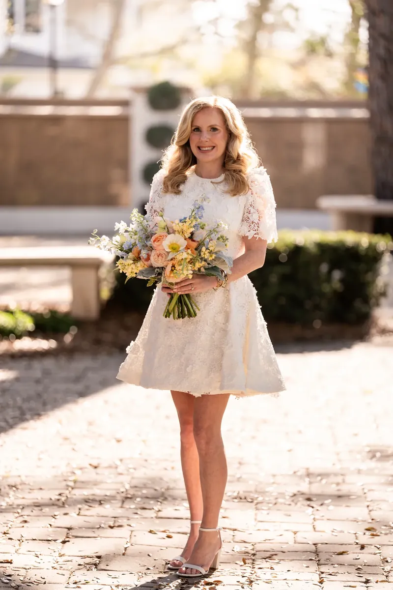 Chauncey in her white lace dress holding the bouquet in the courtyard