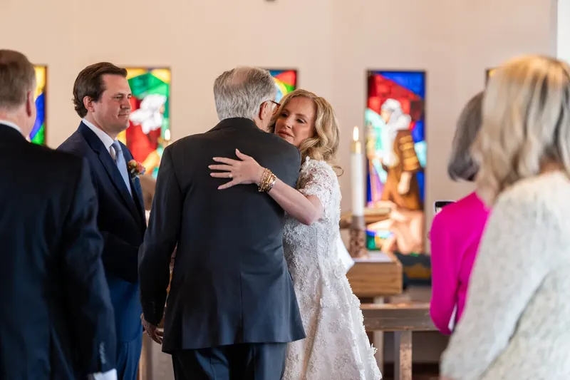 Chauncey hugging her father inside the chapel with stained glass windows behind them