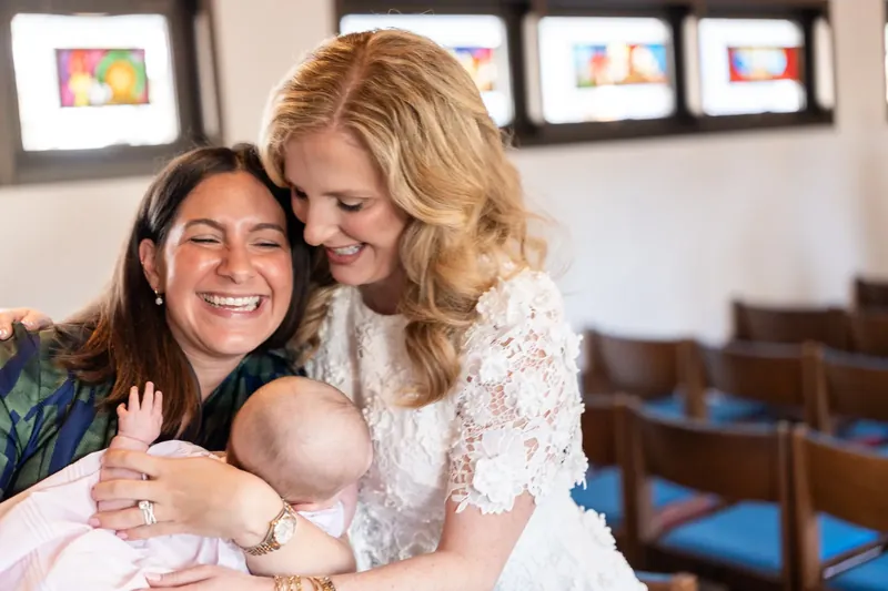 Chauncey laughing with a friend and baby in the chapel pews