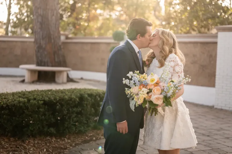 Golden hour kiss in the courtyard with the bouquet