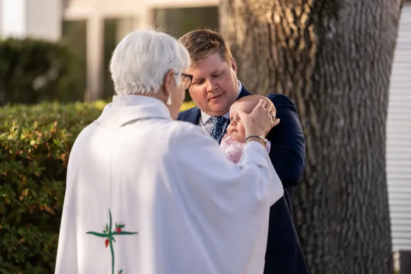 The officiant blessing a baby held by a family member outside