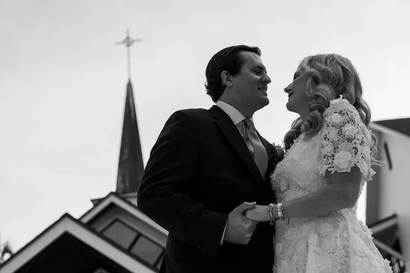 Black and white portrait of the couple with the church steeple behind them