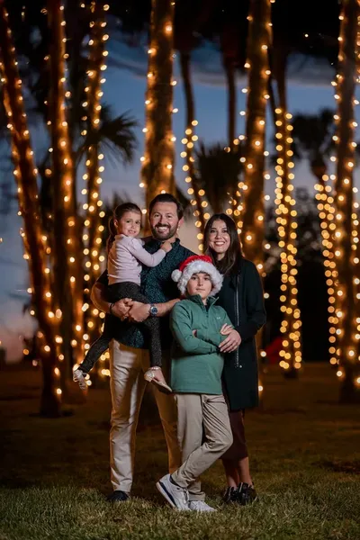 Family portrait with palm trees wrapped in holiday lights at sunset during St. Augustine Nights of Lights