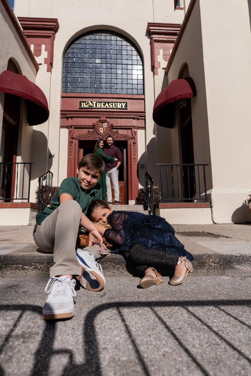 Kids playing in front of The Treasury entrance while parents watch from doorway