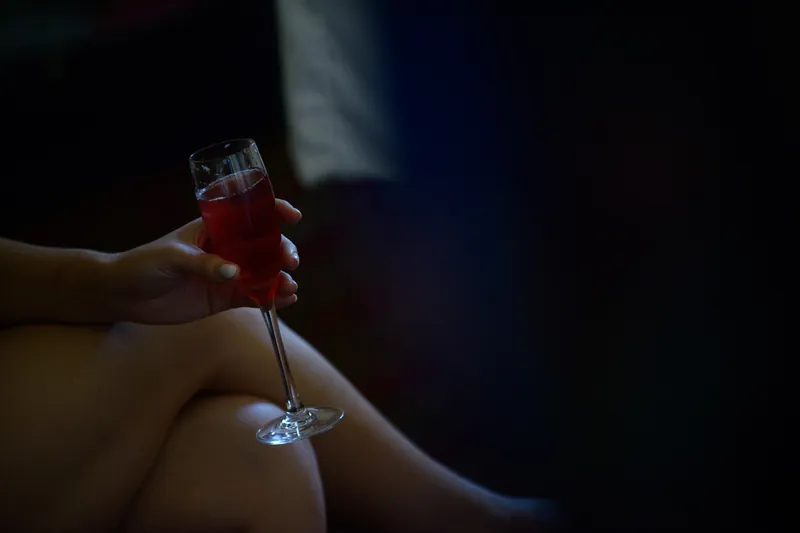 A hand holds a glass of red wine against soft golden light during the reception.