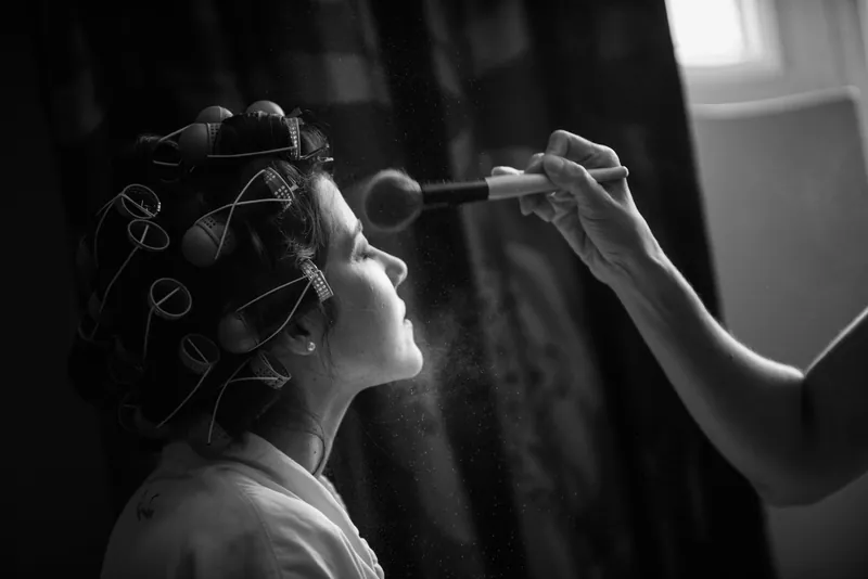 A makeup artist applies finishing touches to Choko's face as she sits in profile.