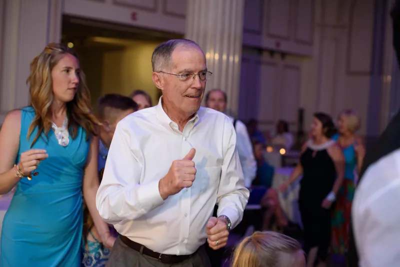 A man in a white shirt dances energetically while guests watch at The Treasury on the Plaza.