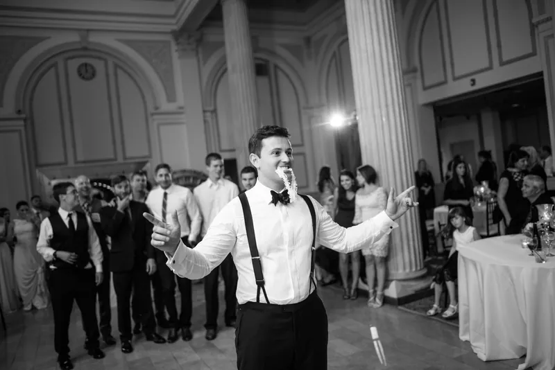 Michael spreads his arms wide while dancing to celebrate with guests in the formal reception hall.