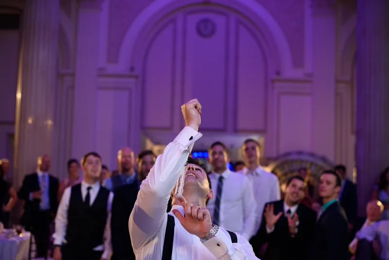 Michael raises his fist in celebration as guests applaud beneath the purple-lit arched ceiling of The Treasury on the Plaza.