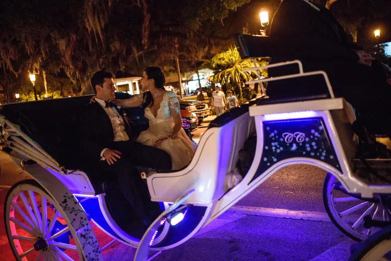 Choko and Michael sit together in a neon-lit carriage decorated with purple and pink lights after their reception.