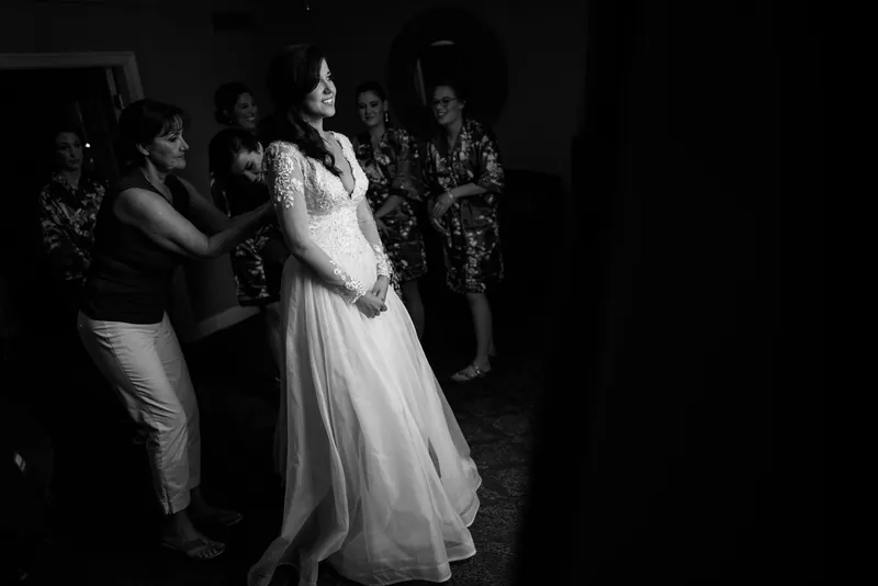 Choko stands in her white wedding gown surrounded by family members wearing sequined outfits in low lighting.