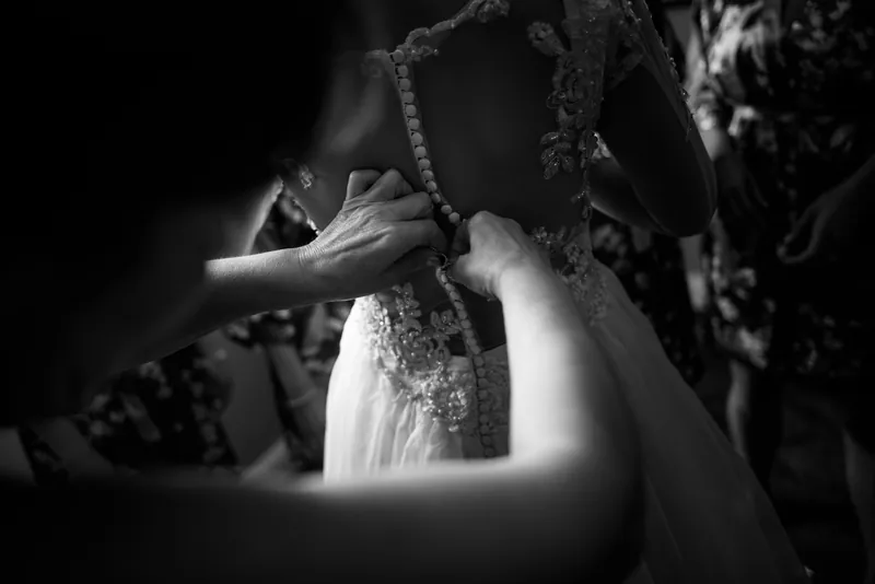 Hands fasten Choko's beaded wedding dress as she prepares at Casa Monica Resort & Spa.
