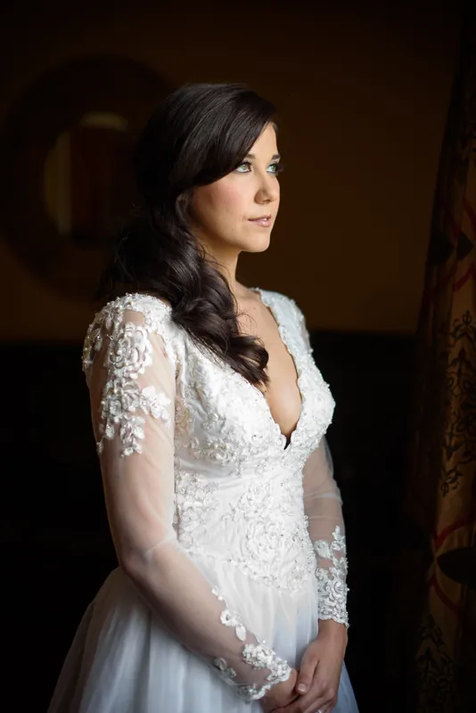 Choko stands in profile wearing an intricate beaded white gown, her dark hair cascading over one shoulder.
