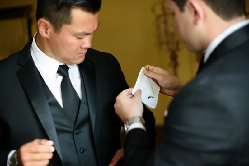 Michael adjusts Choko's cufflinks while both wear formal black suits at Casa Monica Resort & Spa.
