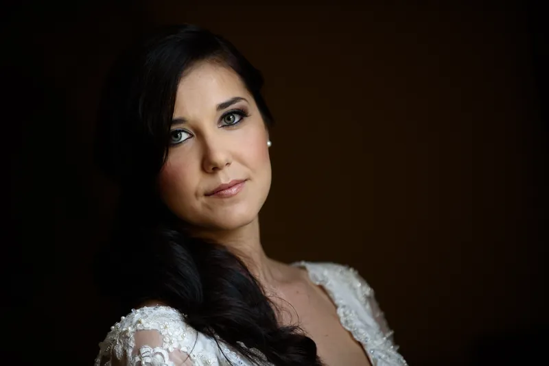 Choko tilts her head, dark hair flowing over her shoulder in an ivory lace wedding gown.