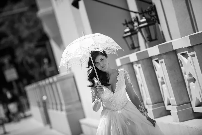 Choko holds a white umbrella while standing on a columned porch in downtown St. Augustine.