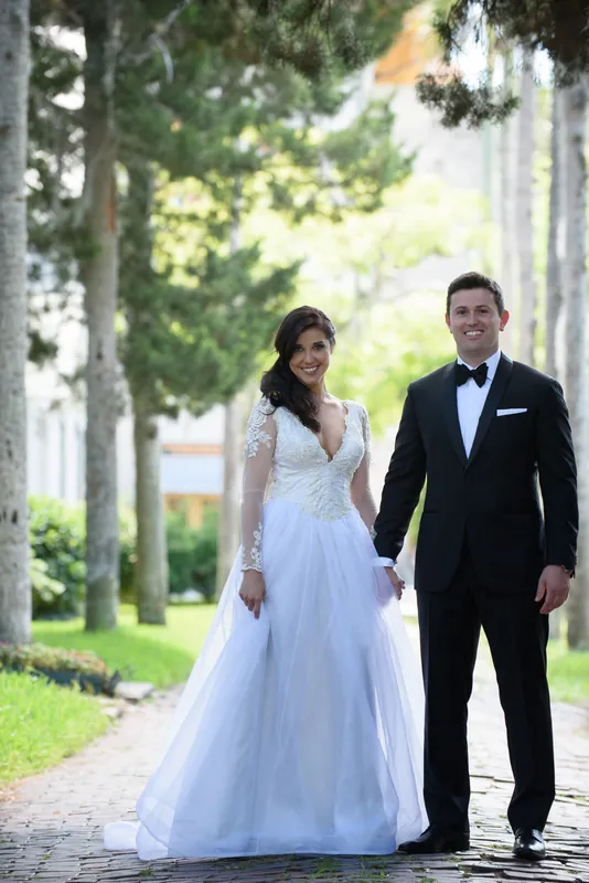 Choko and Michael walk side by side down a tree-lined street in Downtown St Augustine, she in a flowing white gown and he