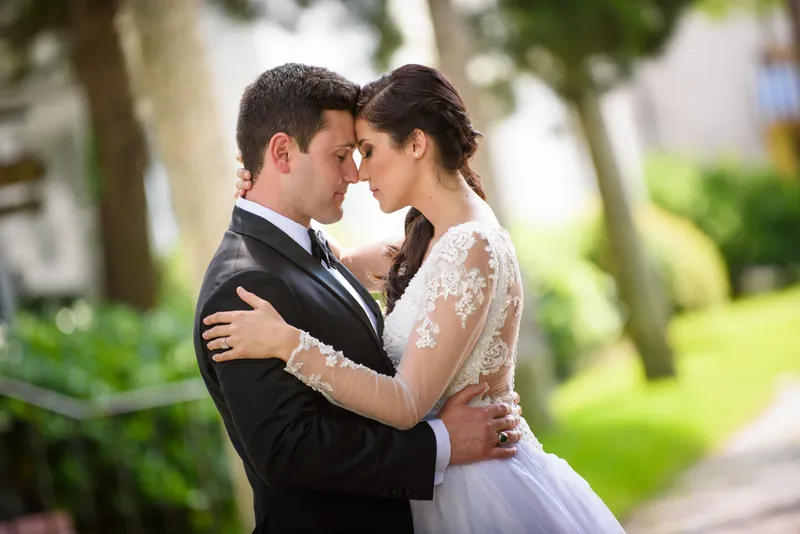 Michael holds Choko close as they embrace outdoors, her lace sleeve visible against his dark suit jacket.