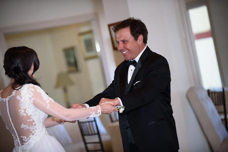 Michael in a black tuxedo reaches out to take Choko's hand as she approaches in her white lace gown at The Treasury