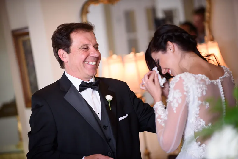 Choko and Michael laugh together indoors, Choko touching his chest as he grins at her during their first look at The Treasury