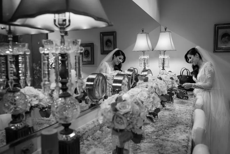 Two women in white dresses arrange elaborate white floral centerpieces in an elegant indoor salon at The Treasury