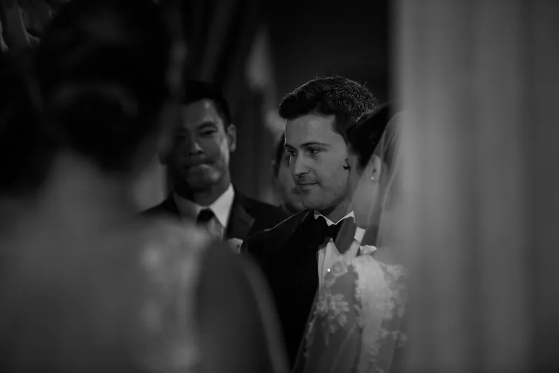 Michael gazes forward in his tuxedo while attendants stand nearby during the wedding ceremony.