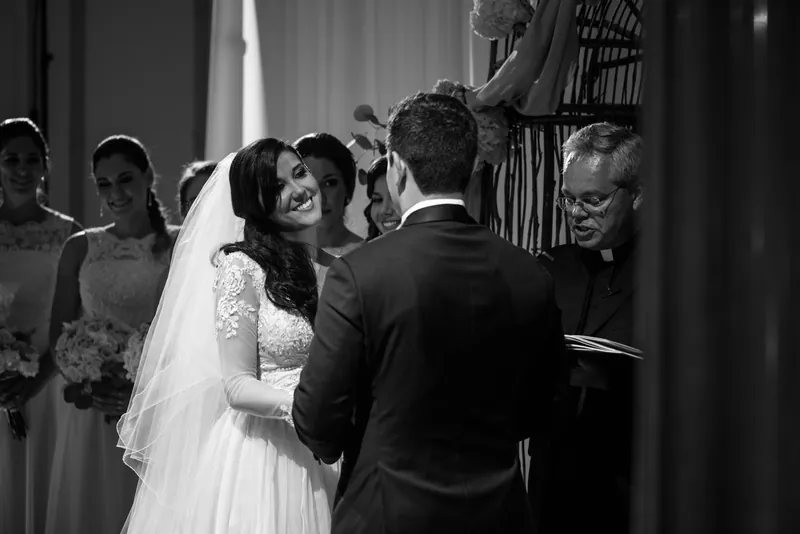 Choko and Michael clasp hands during their vows as an officiant stands beside them.