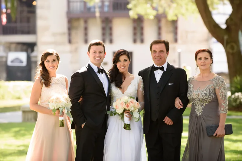 Five family members stand together on the lawn in formal wear holding white bouquets.