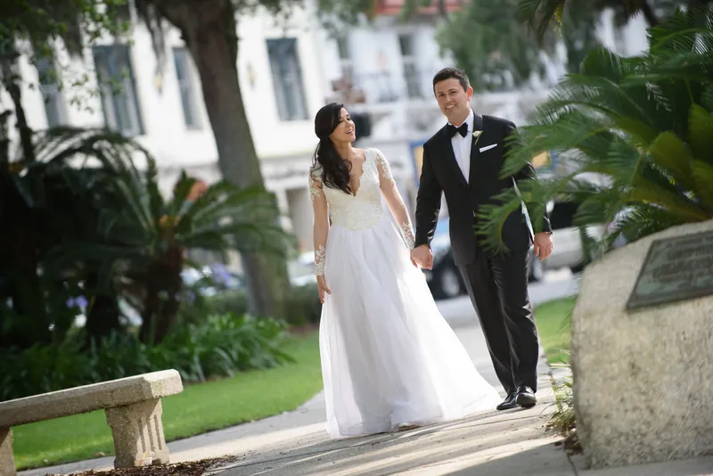 Choko and Michael walk hand-in-hand down a tree-lined path past colonial architecture in Downtown St Augustine.