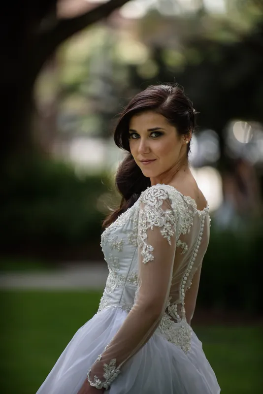 Choko wears an elegant lace-back wedding gown with delicate cap sleeves while posing outdoors in Downtown St Augustine.