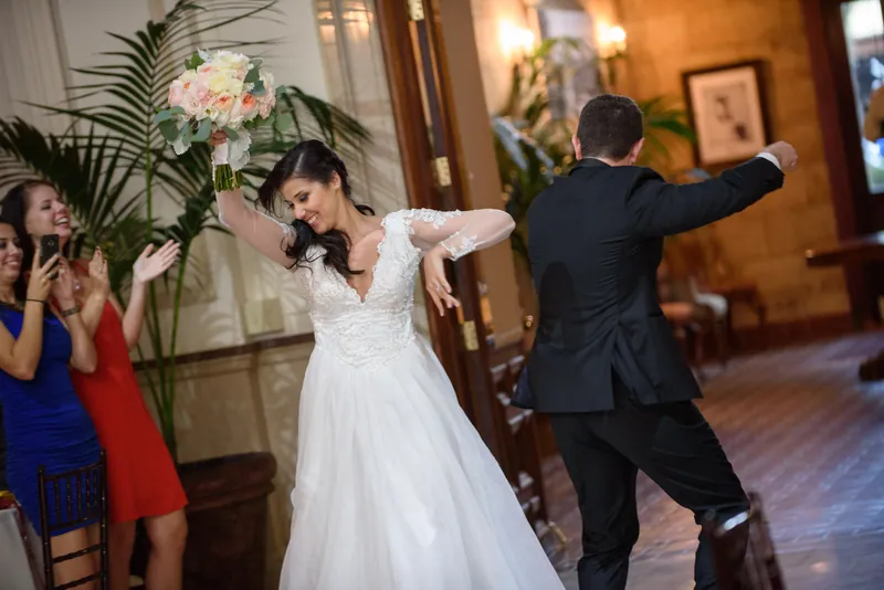 Choko and Michael dance together surrounded by guests in formal attire at The Treasury on the Plaza reception.