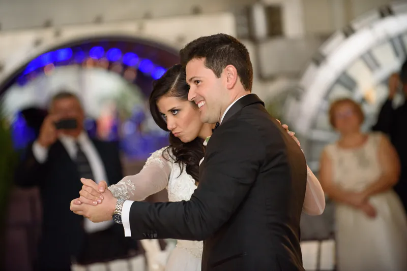 Choko and Michael share a close dance as blue uplighting glows behind them during their first dance celebration.