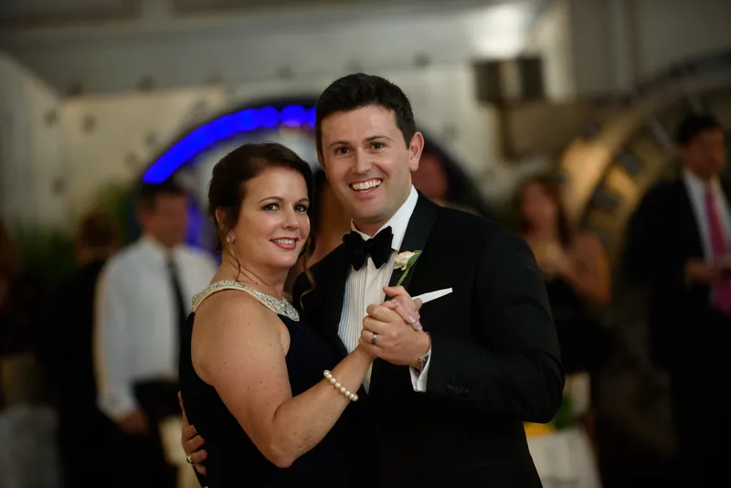 Choko and Michael smile while dancing together, his hand at her waist and hers at his shoulder during their reception.