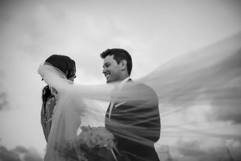 Choko and Michael embrace in profile against a dramatic cloudy sky, rendered in black and white.