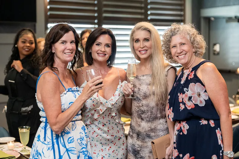 Five women hold champagne glasses and smile together during the celebration at Chophouse at Nocatee.