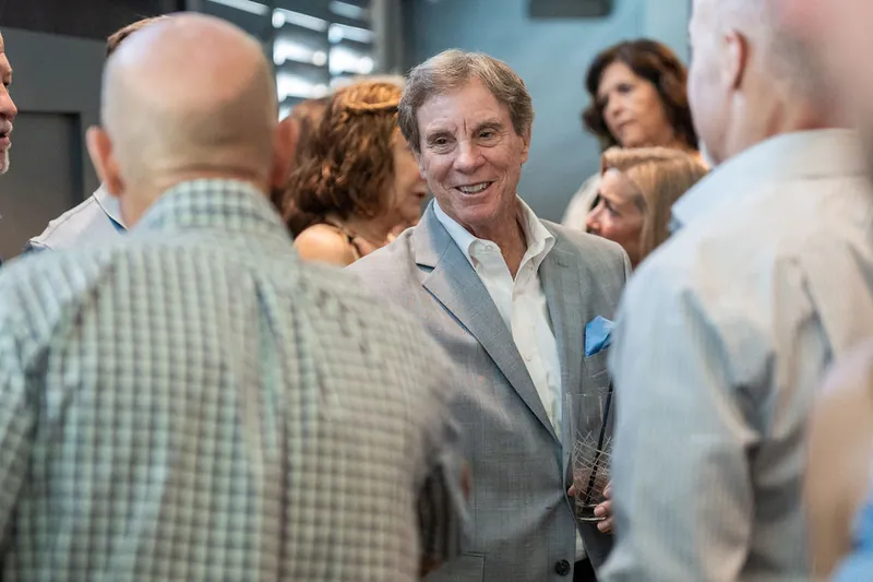 A man in a gray blazer smiles while chatting with guests at Chophouse at Nocatee.