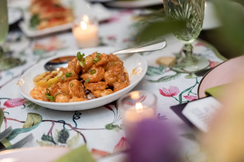 Shrimp appetizers arranged on a white plate at a floral-printed table with glassware and candles at Chophouse at Nocatee.