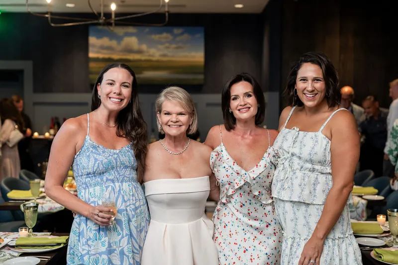 Four women smile at Chophouse at Nocatee, wearing patterned and solid summer dresses in pastel shades.