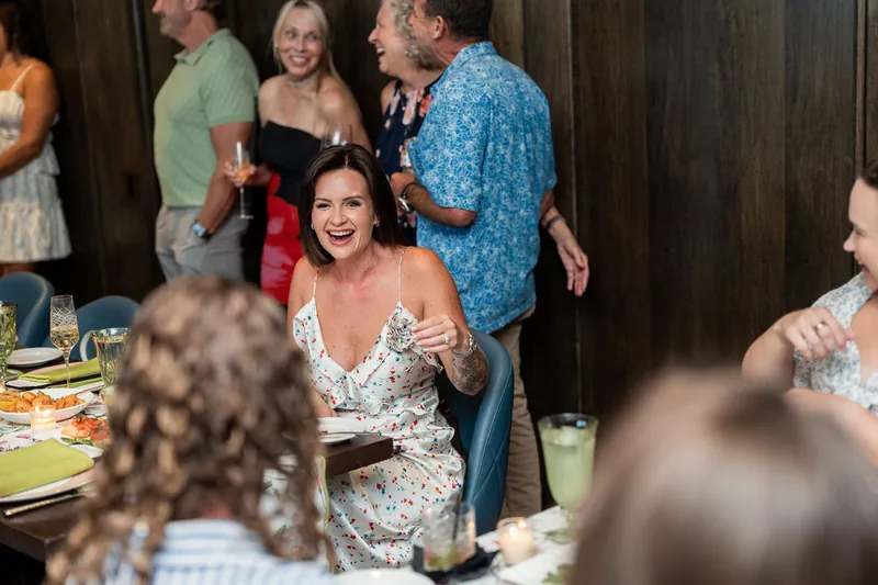 Cleo in a sequined white gown chats with guests at Chophouse at Nocatee, surrounded by family and friends at an indoor
